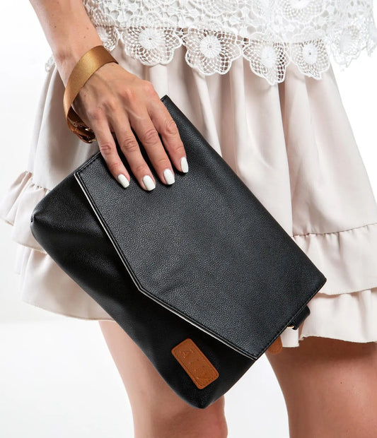 A woman holding a black handbag with a long strap and wrist strap. Lightweight at 0.3 kg, featuring a removable wet wipes pocket. Designed in Europe by Ally Scandic for stylish, convenient storage.