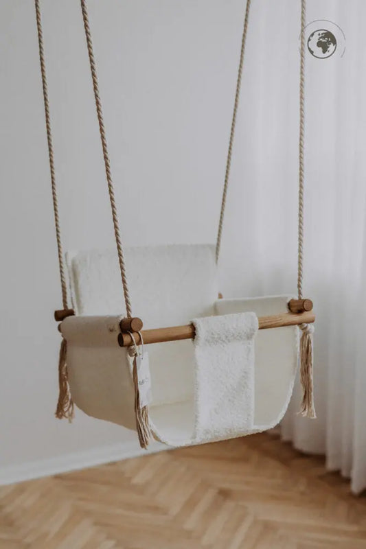 A luxurious Baby Swing in Bouclé Snow White, made from recycled materials and oak wood poles, certified for safety and comfort. Includes pillow and carabiners. Dimensions: 41 x 41 cm.