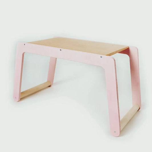 A pink and white children's small desk with legs, made of birch plywood. Functional and safe for kids, providing a creative workspace. Dimensions: 56 x 30 x 27 cm. Made in Europe.