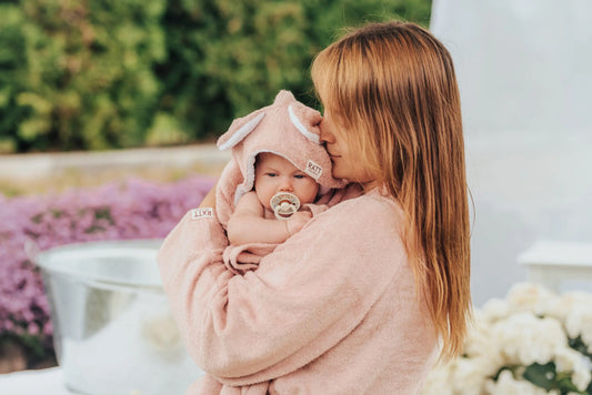 A woman holds a baby wrapped in a Hooded Baby Bath Towel with RABBIT ears. Crafted from bamboo terry for delicate skin, charming design with superior quality for newborns.