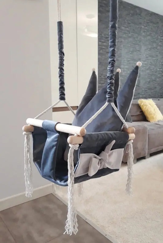A grey Crown Shaped Cushion Swing for children's rooms, featuring velvet plush material, Cleanbo tech for easy cleaning, sturdy pinewood construction, and a podium crown for comfort.