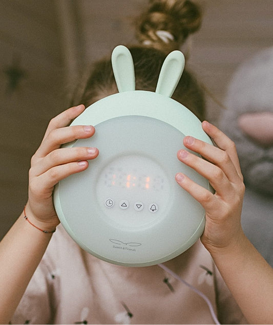Person holding Rabbit Lamp with Alarm Clock, featuring amusing ears, sunrise & sunset simulation, touch control, clock, and nature sounds.