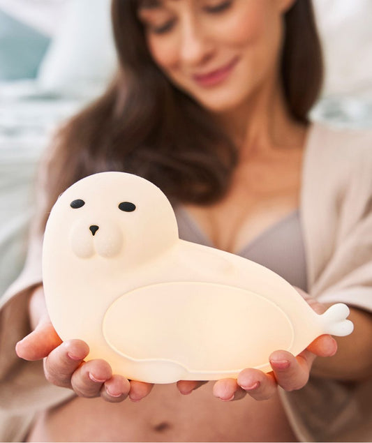 Woman holding a white Seal Silicone Lamp with Remote, featuring a playful seal shape, soft touch, remote control, and safe, BPA-free silicone material.