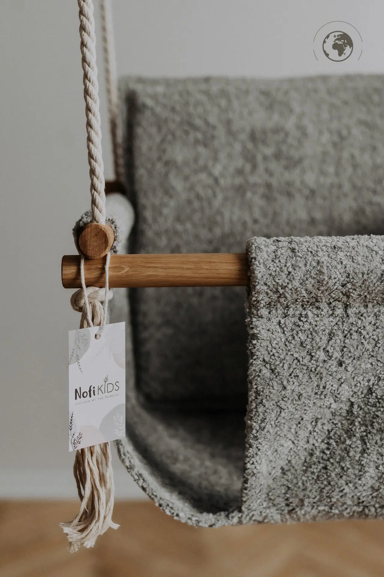 A close-up of a luxurious Baby Swing in Bouclé Stone Grey, showcasing oak wood poles and soft bouclé cloth. Crafted from recycled materials for safety and style.