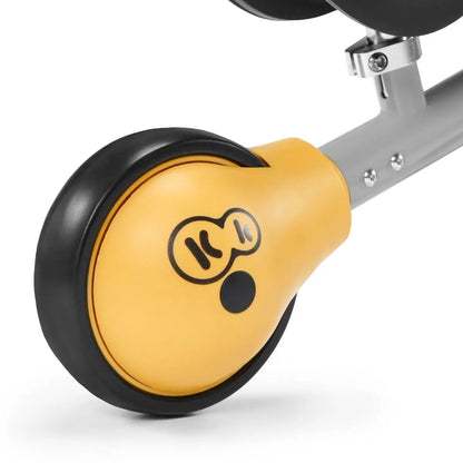 Close-up of Balance Bike CUTIE's wheel with yellow logo, ball-bearing rear wheel, adjustable seat, rubber non-slip handles, and strong steel frame for safe, durable play.