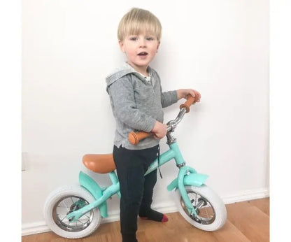 A child on a balance bike MARSHALL, featuring adjustable saddle and handlebar height, 10 air tires, sturdy frame, soft saddle, and non-slip grips. Supports balance and motor skill development.