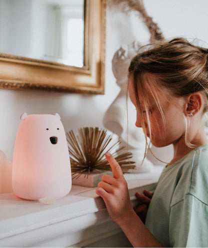 A white silicone lamp in the shape of a teddy bear with small ears and a round belly, providing soothing light for bedtime routines.