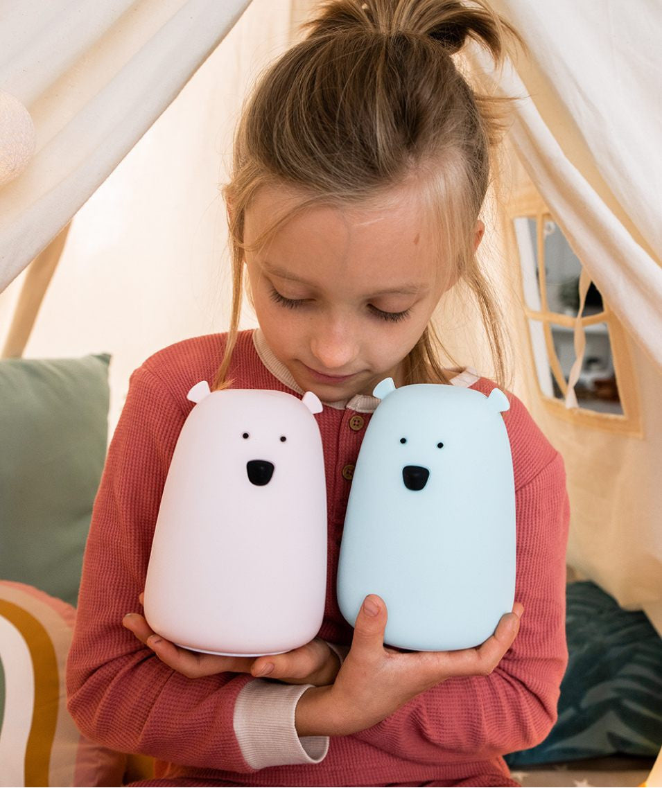 A girl holding a white and blue teddy bear lamp with a remote control, soft silicone material, LED technology, and multifunctional features.