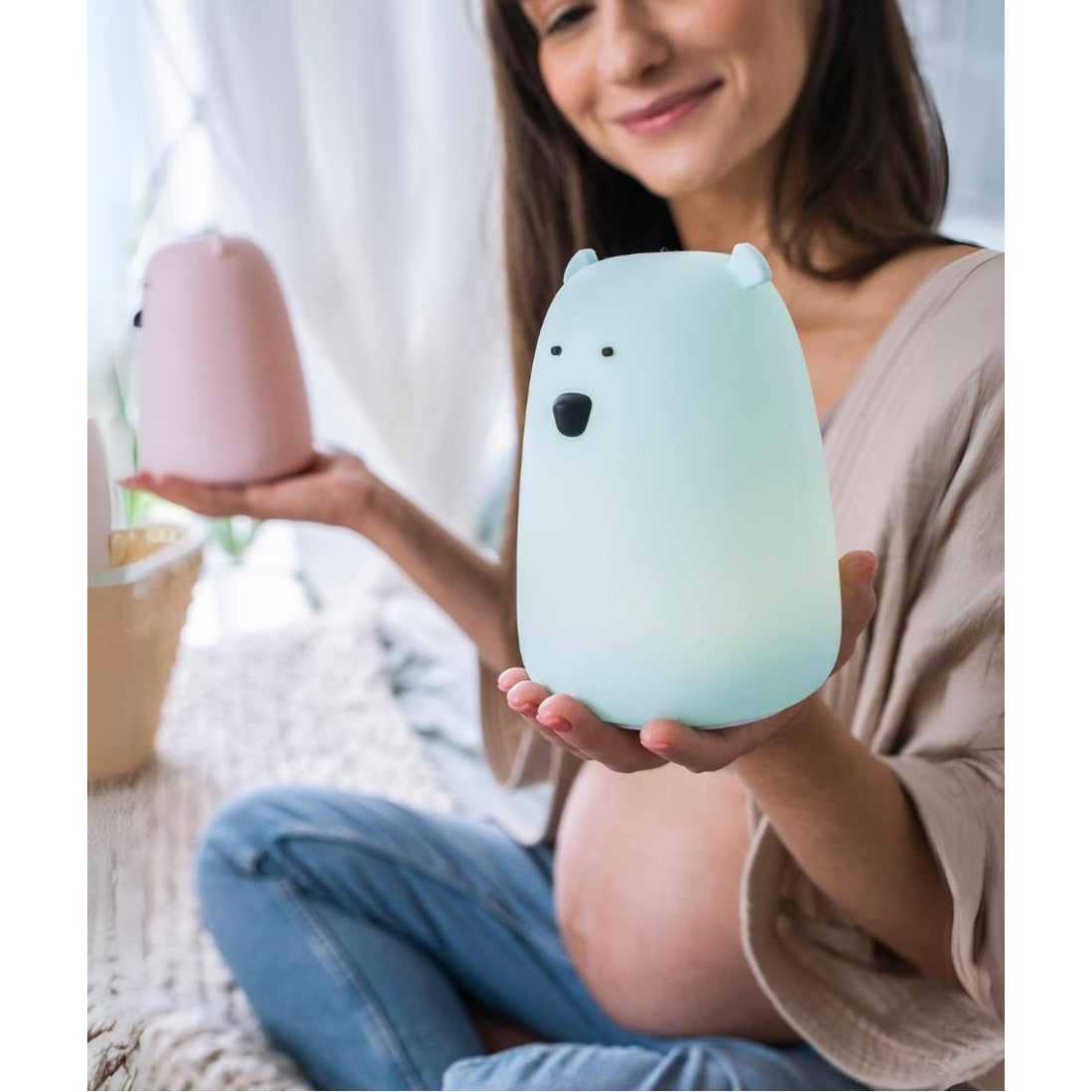 A woman holding a light-up teddy bear lamp with remote control, perfect for comforting children at night. Soft, silicone material, multifunctional remote, and safe for kids.