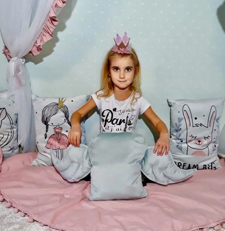 A girl sits on a bed with pillows, holding a decorative cushion Wings - Grey. Handmade in Europe, velvet material, 100% polyester, siliconized sintepon padding.
