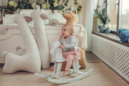 A baby enjoys a Giant Plush Toy Alpaca - Beige, a versatile companion doubling as a cozy pillow or playful playmate. Handmade with soft vegan fur, eco-friendly materials, and safety standards.