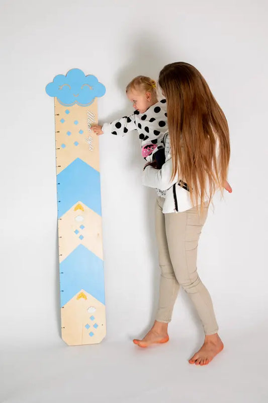 A woman holding a child on her back, hugging a person, and a ruler with a blue and white design. Growth Chart - Light Blue: A charming keepsake for tracking child's growth, with cloud and raindrop design.