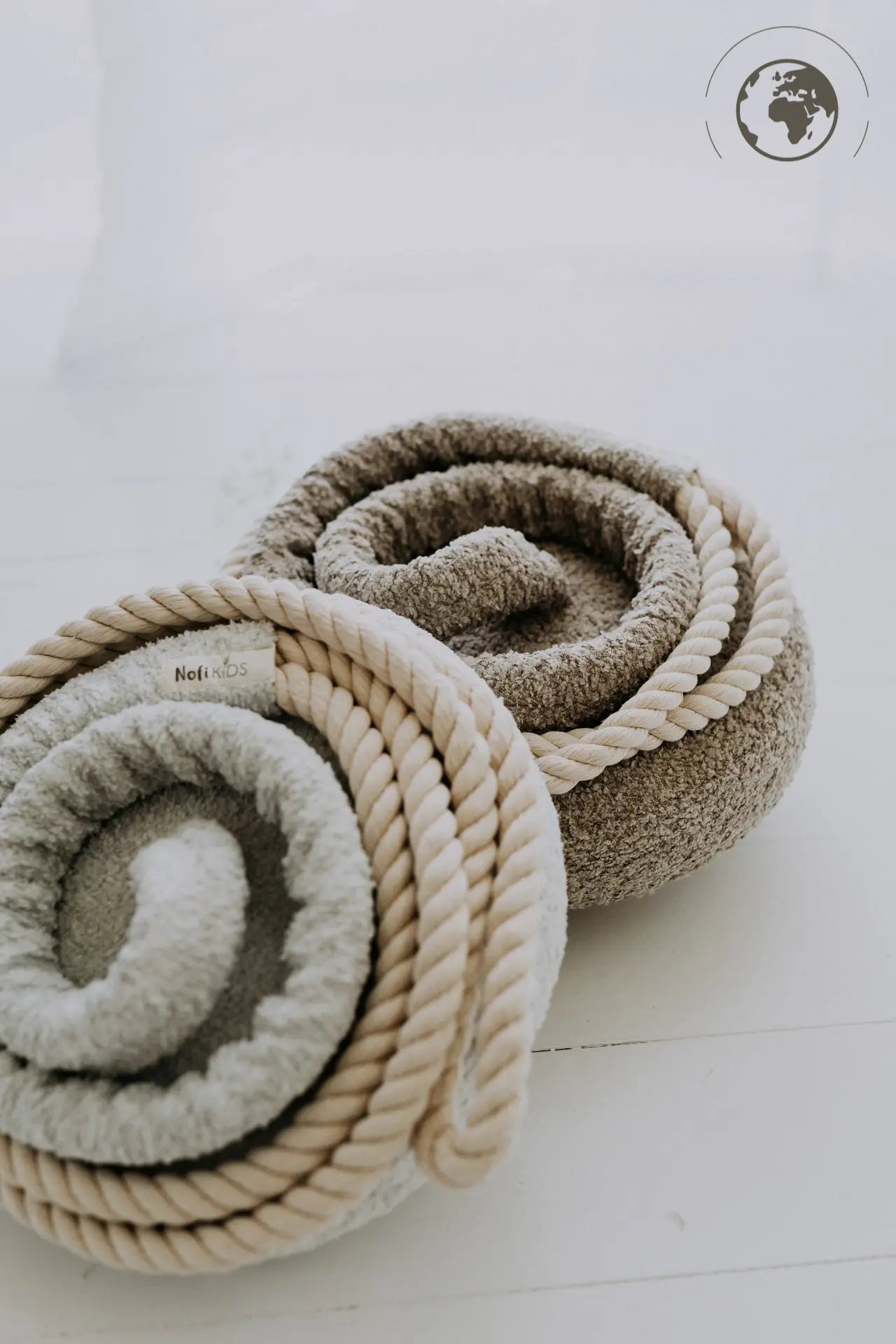 A close-up of the HopOn Swing - Bouclé Ice Grey, featuring a fabric seat, cotton rope, and carabiner. Designed for indoor use, supporting physical development with a 100 kg load capacity.