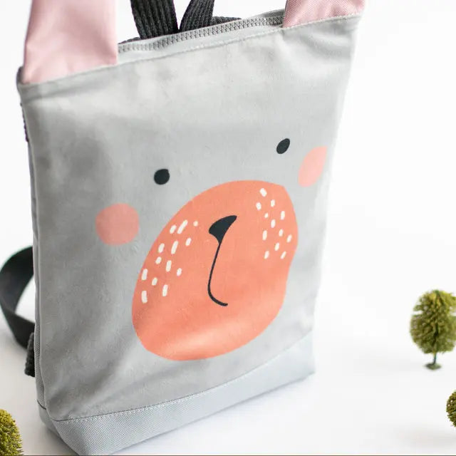 Kids backpack featuring a grey bear face design, ideal for young adventurers. Made of velvet and waterproof polyester, with adjustable beige shoulder straps. Small size, perfect for ages 2-6.