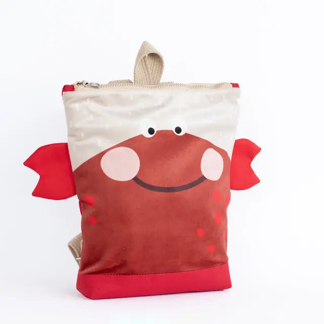 A red and white kids backpack featuring a smiling crab design. Made of velvet and waterproof polyester with adjustable shoulder straps and inside pockets. Ideal for young explorers aged 2-10.