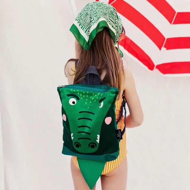 A toddler-friendly CROCODILE backpack for kids aged 2-6. Features a crocodile face design, velvet top, waterproof polyester bottom, adjustable straps, zipper closure, and two inside slip pockets.