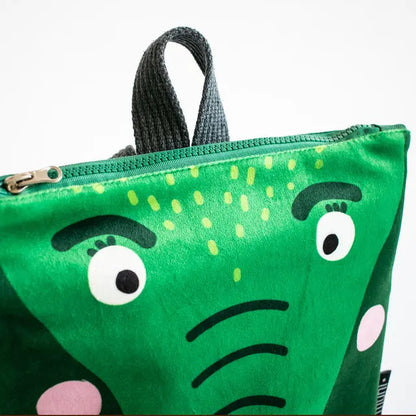 A small kids backpack featuring a green bag with a face design resembling a crocodile. Made of velvet and waterproof polyester, with adjustable shoulder straps and two inside pockets.