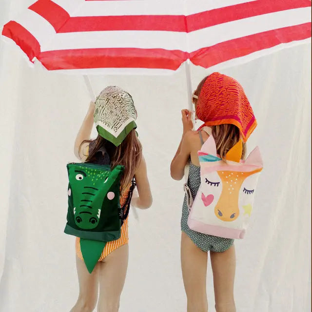 Two girls in swimsuits and hats with a Crocodile kids backpack, perfect for pre-school adventures. Features a cute crocodile design, velvet top, sturdy polyester bottom, adjustable straps, and zipper closure.