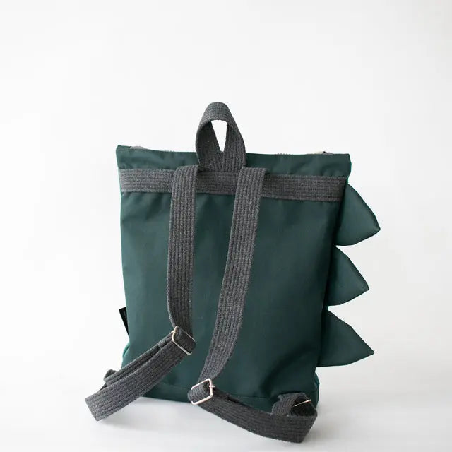 A kids backpack featuring a prehistoric Dinosaur design, with adjustable shoulder straps, zipper closure, and slip pockets. Available in small and large sizes.