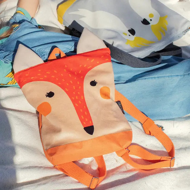 Kids backpack featuring a fox design on velvet fabric. Waterproof polyester bottom, orange lining, and beige shoulder straps. Zipper closure, adjustable straps, and two inside pockets. Available in small and large sizes.