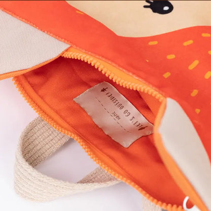 Close-up of a kids backpack featuring a fox design. Velvet top with printed fox motif, waterproof orange polyester bottom, beige shoulder straps, and zipper closure.