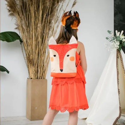 A girl wearing a fox backpack, perfect for outdoor adventures. Velvet top with a painted fox design, waterproof polyester bottom, adjustable straps, and ample storage space. Ideal for kids aged 3-9.