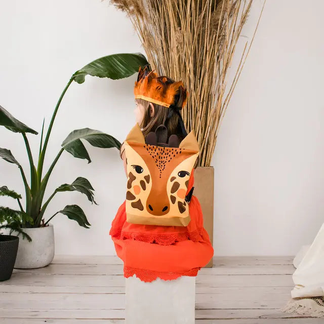 A child wearing a giraffe backpack with velvet top and sturdy polyester bottom. Features adjustable straps, zipper closure, and two slip pockets inside. Ideal for outdoor adventures.