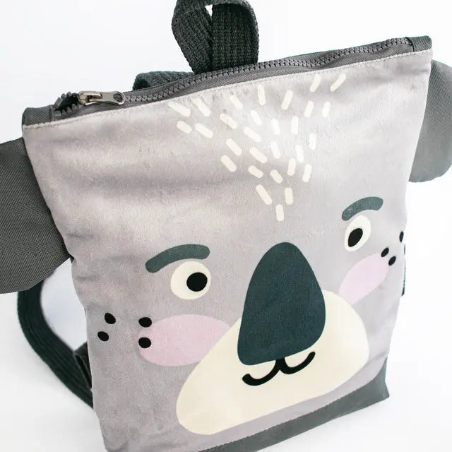 Kids backpack featuring a grey bag with a cartoon koala face design. Made of velvet and waterproof polyester, with adjustable beige shoulder straps and two inside slip pockets. Ideal for outdoor adventures.