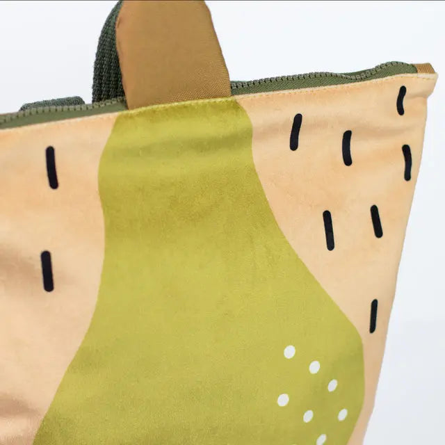 A close-up of a kids backpack featuring a pear motif. Made of velvet and waterproof polyester, with adjustable straps, zipper closure, and inner pockets. Ideal for young explorers aged 4-10.