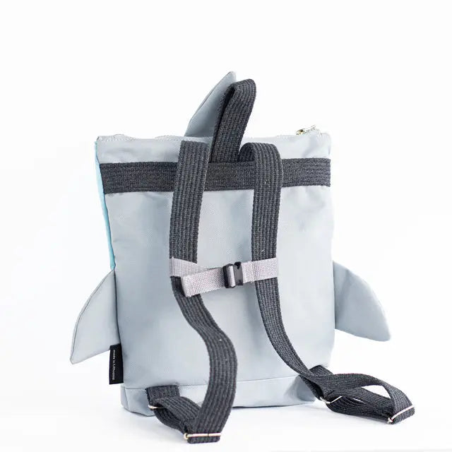 A kids backpack featuring a shark design, perfect for outdoor adventures. Made of velvet and waterproof polyester, with adjustable beige shoulder straps and zip closure.