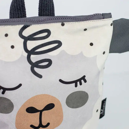 Close-up of Kids backpack - Sheep featuring a black letter t logo on tan surface. Velvet top with Sheep design, waterproof polyester bottom, adjustable beige straps, and zipper closure. Dimensions vary.