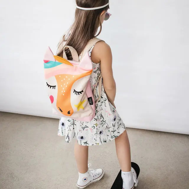 A girl in white shoes stands on a skateboard, wearing a backpack. The backpack features a fox face design and is ideal for kids, with velvet and waterproof polyester materials, adjustable straps, and a zipper closure.