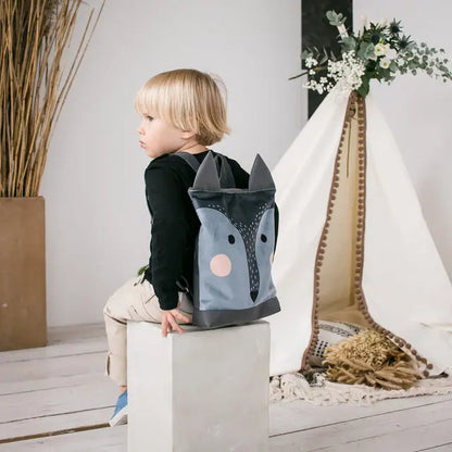 A child's backpack featuring a wolf design, ideal for young explorers. Made of velvet and waterproof polyester, with adjustable straps and zip closure. Available in small and large sizes.