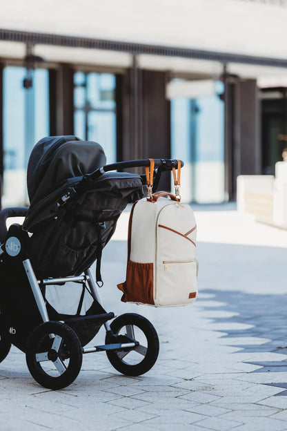 A Cappuccino Diaper Bag with stroller straps, 16 pockets, and laptop compartment. Lightweight, vegan leather, and waterproof. Stylish, organized, and perfect for parents on the go.