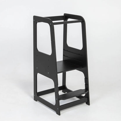 A black chair with a shelf, ideal for young learners and chefs, the Montessori Learning Tower Step Stool for Kids promotes independence and safe exploration in the kitchen.