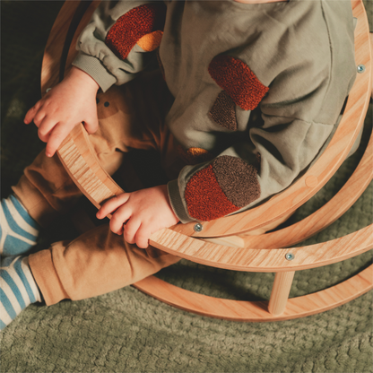 Montessori Toy Rings on a wooden chair next to a baby, highlighting their size and design for enhancing motor skills and creative play.