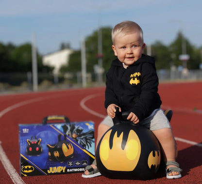 A toddler joyfully bounces on a Batmobile-themed hopper, promoting balance and coordination skills. Ideal for indoor and outdoor play, this durable toy encourages active fun and imaginative adventures.