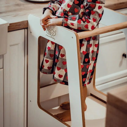 Child in a white Plywood Kitchen Helper Scandi, aiding in kitchen tasks. Birch plywood with melamine coating, adjustable height, promoting independence and safety.