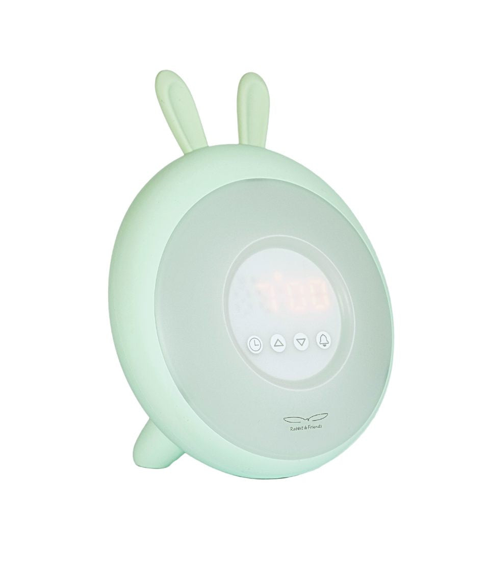 A round alarm clock with rabbit ears and buttons, imitating sunrise and sunset. Features nature sounds, touch control, and snooze function. Dimensions: 19.3 x 15 x 6.9 cm.