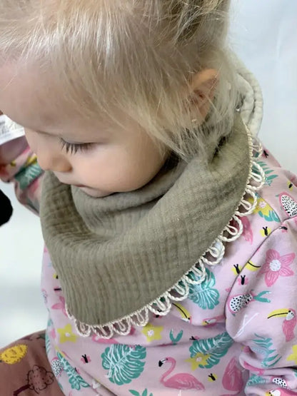 Close-up of a baby wearing a handmade double-sided muslin scarf-bib in khaki. Soft and stylish, designed for ages 6 months to 3 years.