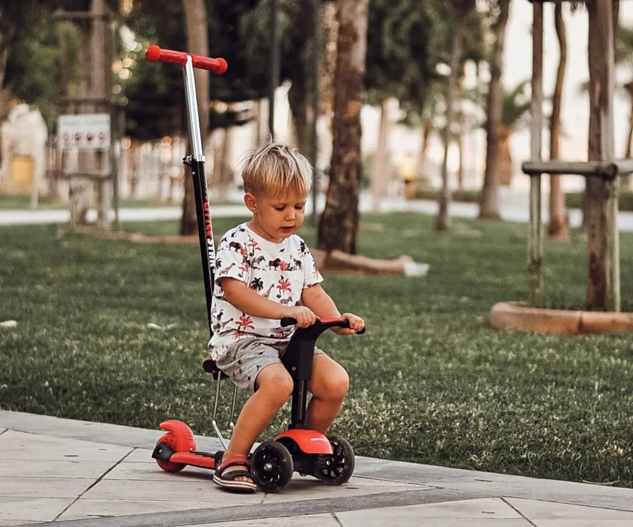 A child on a 3-in-1 scooter with adjustable handlebar height, front wheels that light up, and a seat for toddlers up to 20 kg. Safety gear recommended.