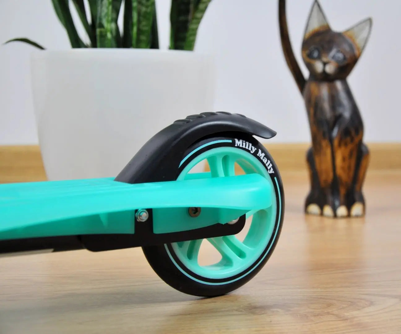 A close-up of the innovative Scooter SMART - Mint with a cat statue, adjustable handlebar, ABEC-5 bearings, PU wheels, and a rear wheel brake.