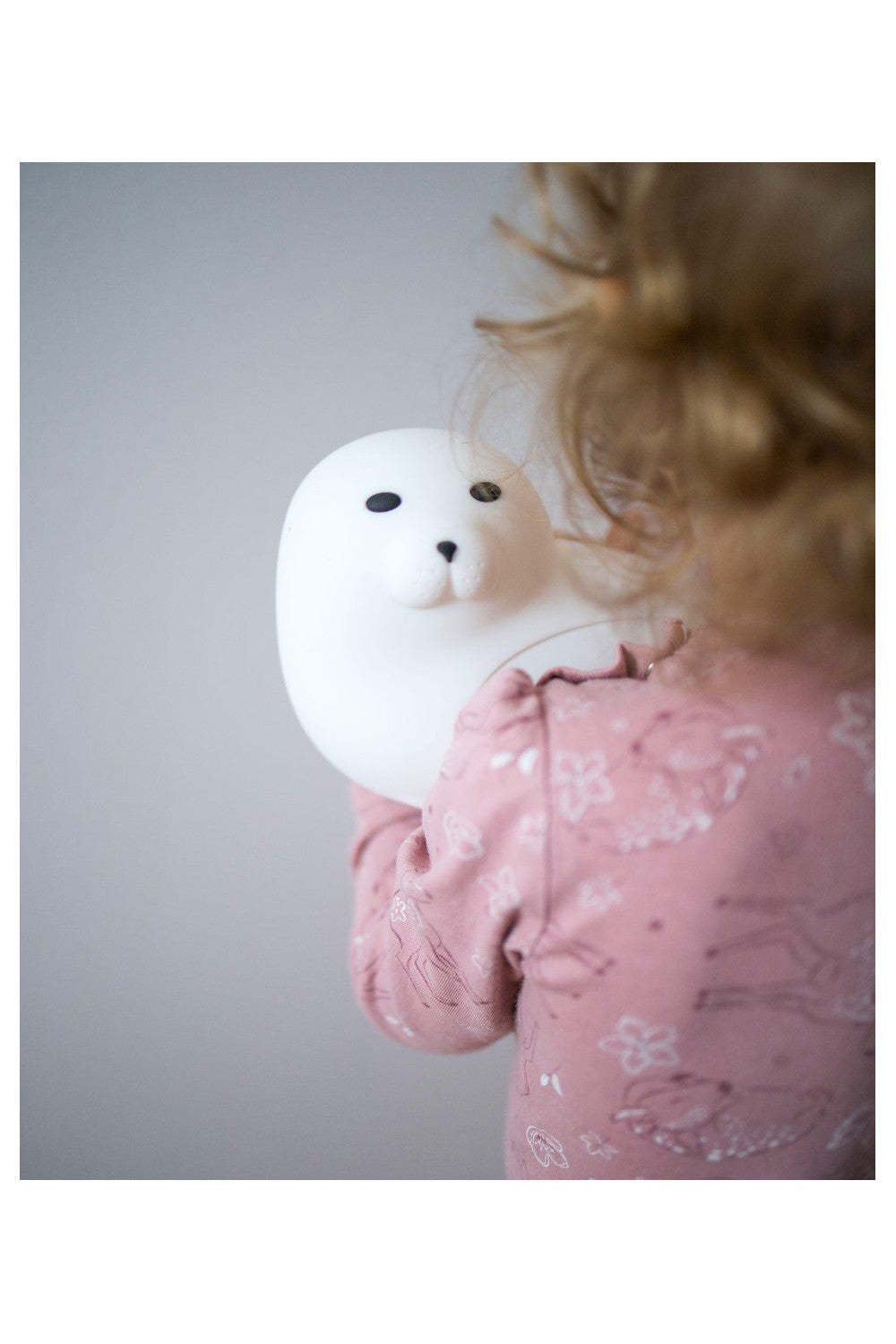 A child holds a Seal Silicone Lamp with remote control, featuring a playful seal shape with large eyes and fins. Soft, touchable, and safe for kids, it lights up in 7 colors.