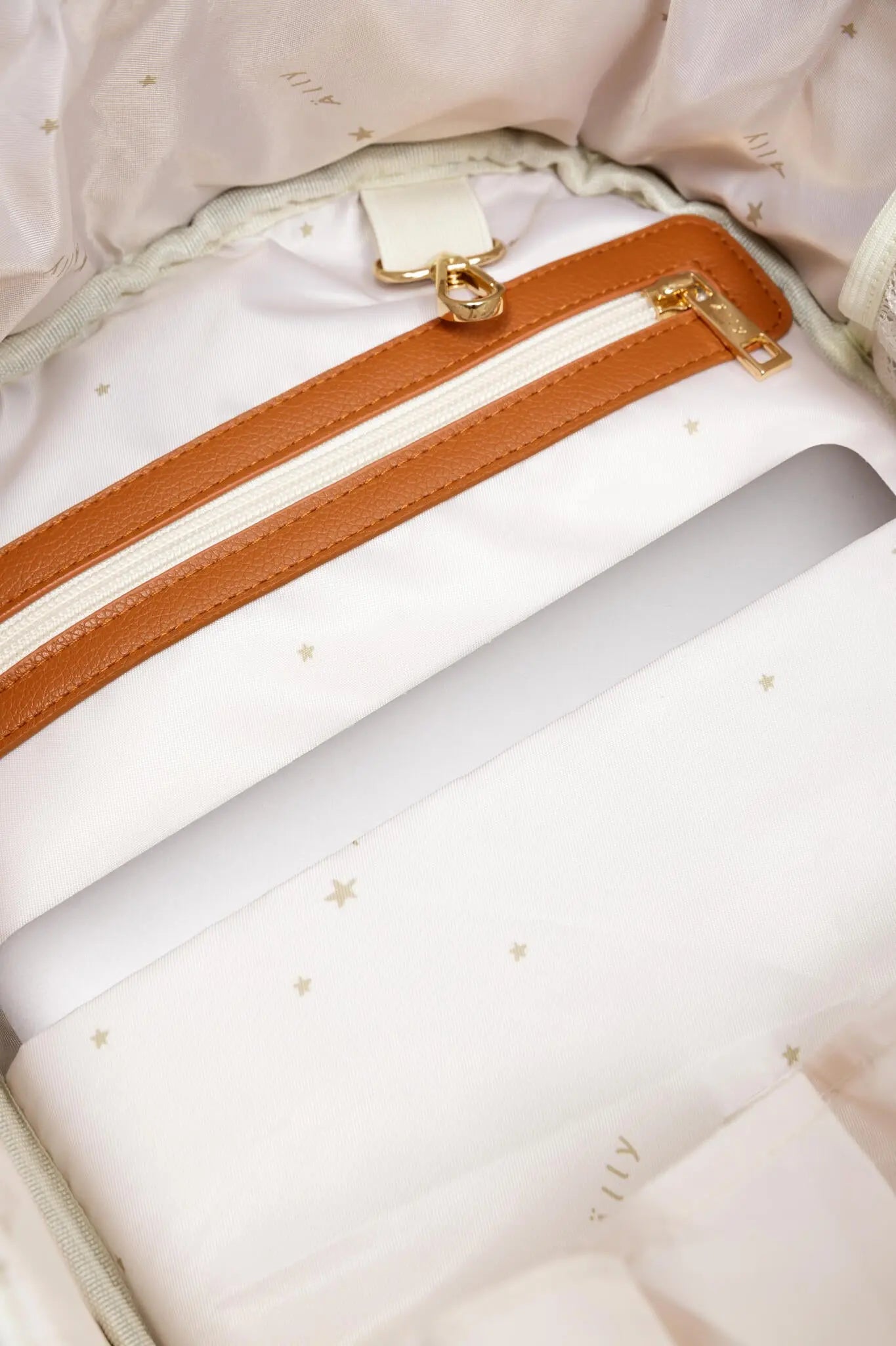 A close-up of a Small Diaper Backpack in Cappuccino color, showcasing a white bag with a zipper, gold accents, and thoughtful pocket organization for on-the-go parents.