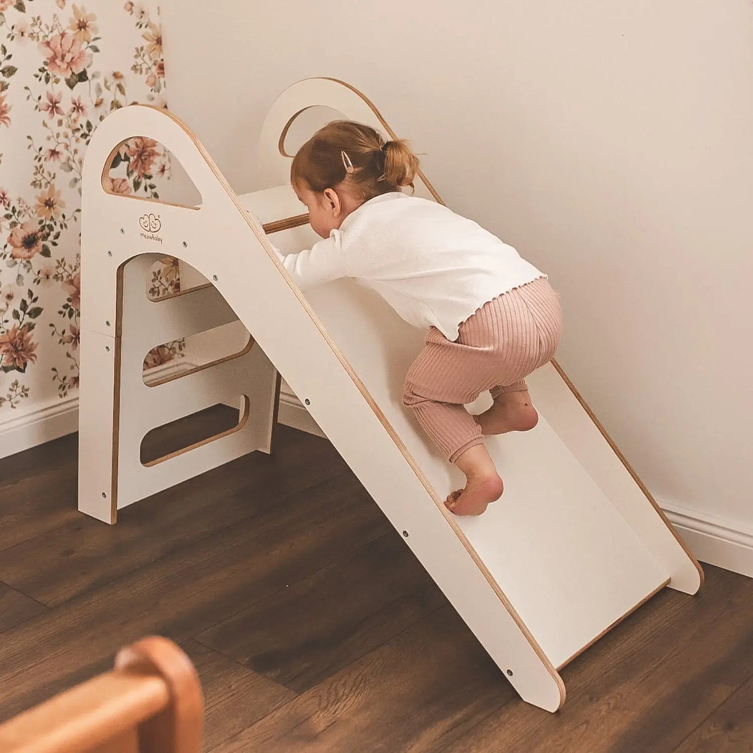 A child climbs a wooden indoor Scandi slide with three steps, promoting motor skills and balance. Measures 87x46cm, made of birch plywood, suitable for kids over 12 months.