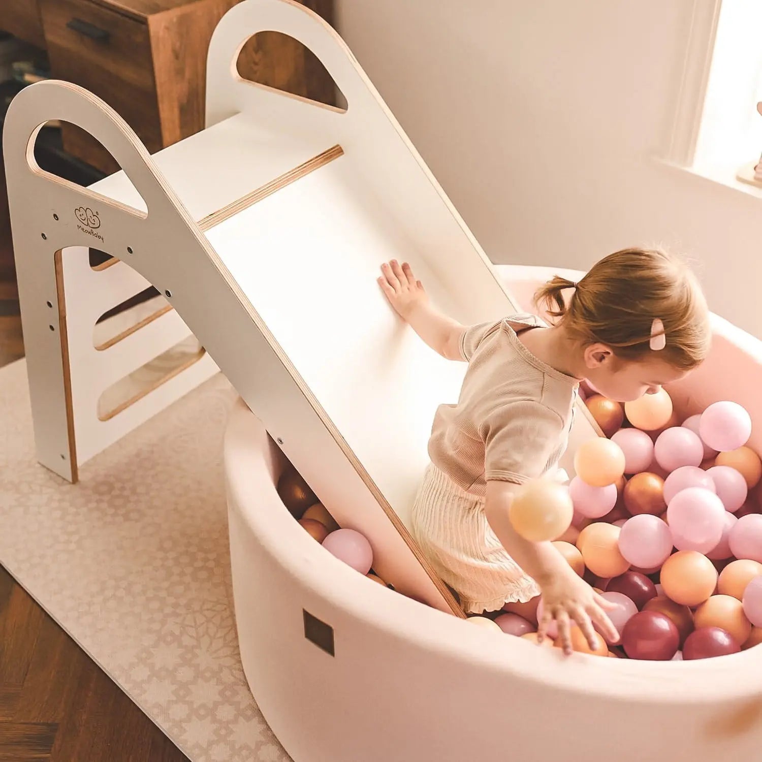 A child playing on a Wooden Indoor Scandi Slide, featuring a stable structure, smooth edges, and comfortable handles for safe sliding fun. Dimensions: 87x46cm.