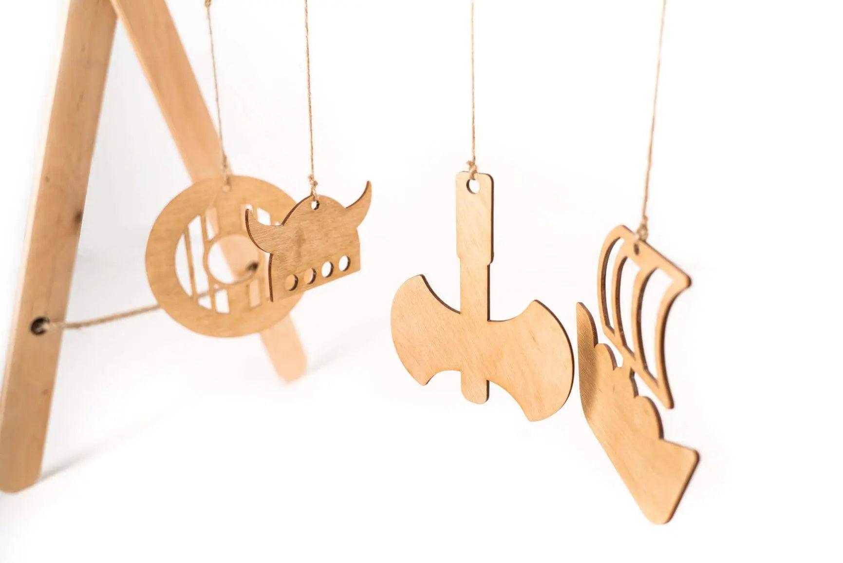 A wooden play gym for babies featuring Viking-themed hanging toys on a stylish frame. Promotes cognitive and motor skills development. Foldable, eco-friendly design. Dimensions: 65 x 59 x 31 cm.