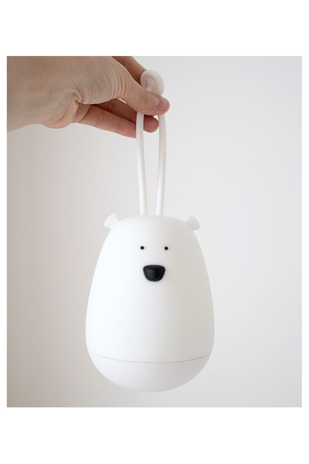 A hand holding a white Hanging Night Light with ears and nose, featuring a silicone fastener, remote control, and soft touch. Ideal for comforting children at night.