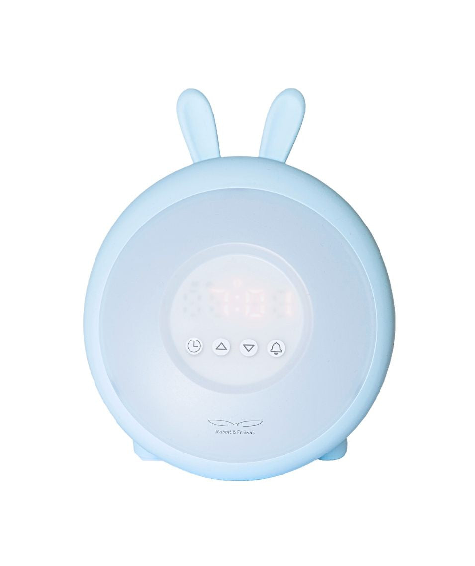 A round white alarm clock with bunny ears, sunrise and sunset light simulation, nature sounds, snooze function, touchpad, and clock. Dimensions: 19.3 x 15 x 6.9 cm. Certificates: CE, RoHS, EN71.