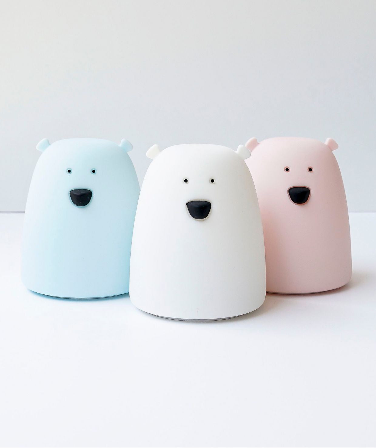 A close-up of the Little Bear Silicone Lamp, featuring a white bear toy with a black nose, emitting a warm, friendly light. Child-safe, touch-operated, multi-colored night light for a cozy ambiance.